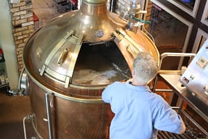 Man with manual agitator stirring mash in a still - brewing and distilling